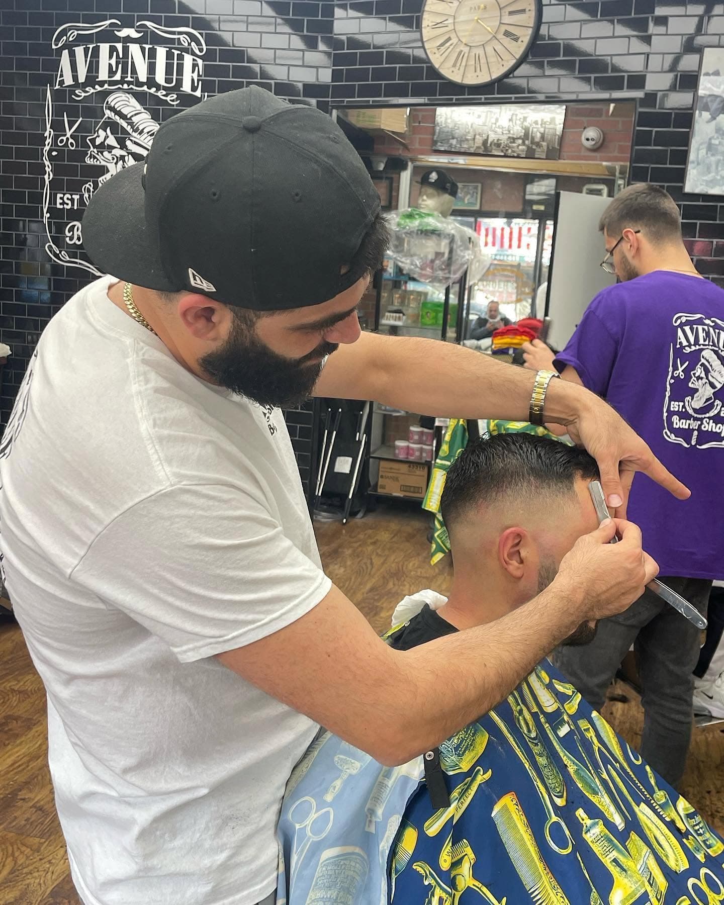 A barber lining up a fade with a straight razor